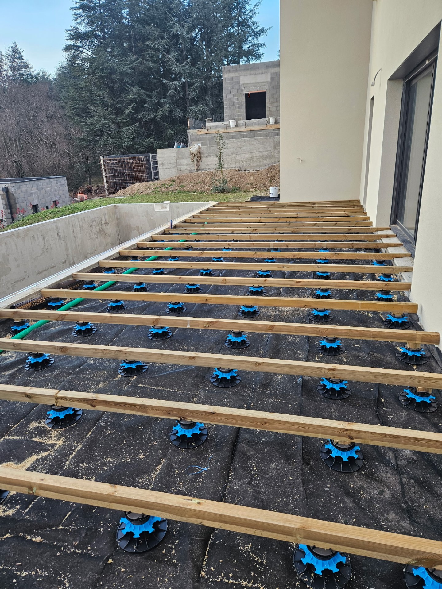 Structure de terrasse sur plots, lambourdes en cours de pose